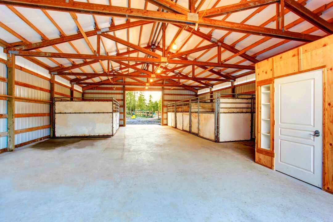 Interior of a pole barn horse building with multiple stalls and a built-in restroom